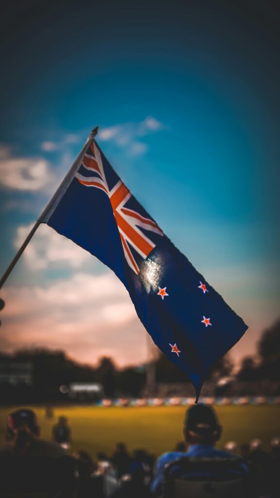 Vibrant New Zealand flag waving with a colorful sky backdrop, capturing patriotism.